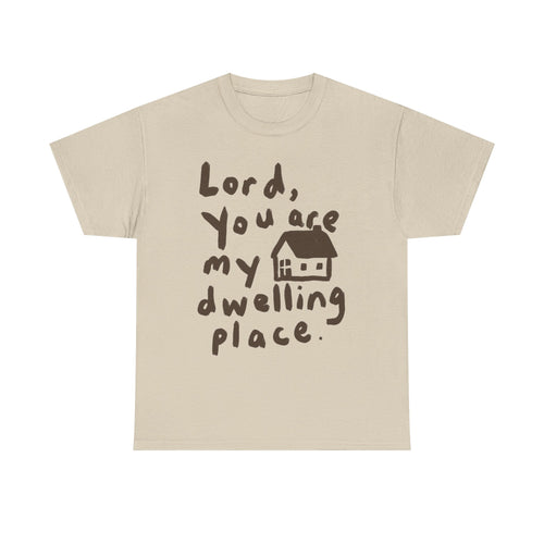 A light beige crewneck t-shirt with a dark brown graphic print that reads 'Lord, You are my dwelling place.' next to a small house illustration, shown on a plain white background.